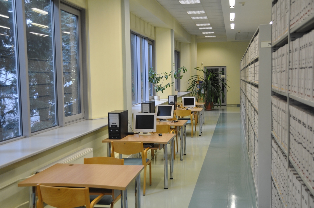 Zdjęcie poglądowe przedstawiające stoliki, komputery i regał z książkami w Bibliotece Chemicznej.