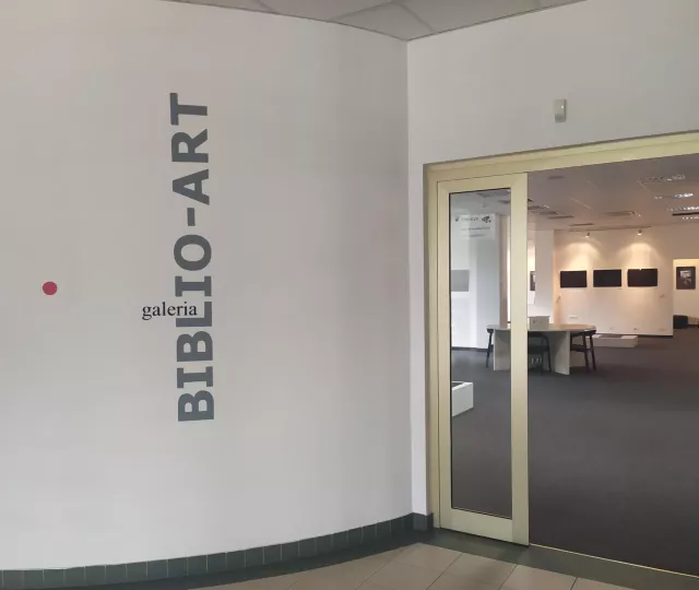 Wejście do Galerii, z lewej strony na białej ścianie logo Galerii Biblio-Art