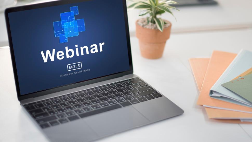 A laptop opened, the screen says ‘WEBINAR’.