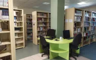 Strefa wolnego dostępu na pierwszym piętrze w Bibliotece Głównej: regały z książkami i stół z komputerami.