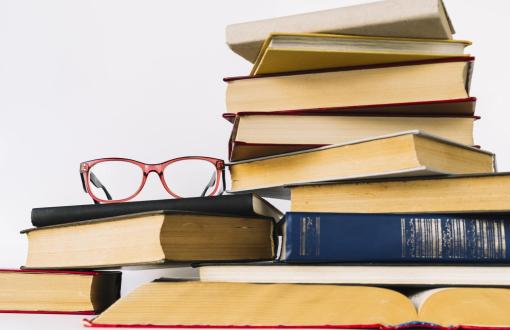 Zdjęcie poglądowe przedstawiające stos książek i okulary