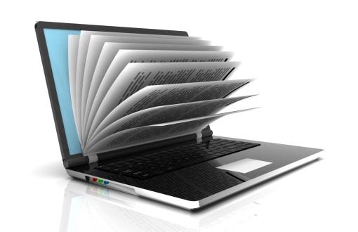 Zdjęcie poglądowe przedstawiające otwarty laptop z wystającymi zadrukowanymi kartkami.
