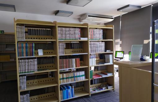 Zdjęcie przedstawiające Czytelnię Czasopism w Bibliotece Budownictwa i Architektury. Widoczne regały, komputery i część lady bibliotecznej.